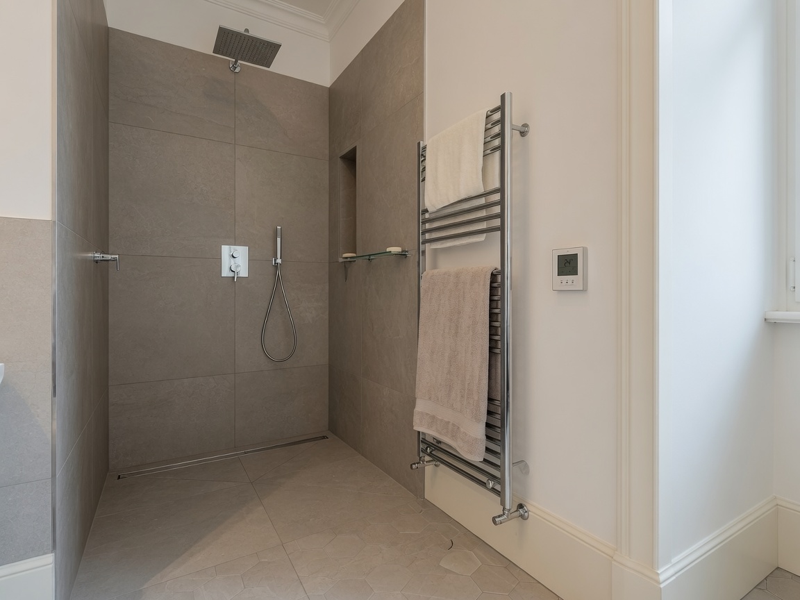 Frisch ausgebautes Bad mit Walk-in-Dusche und Heizkörper